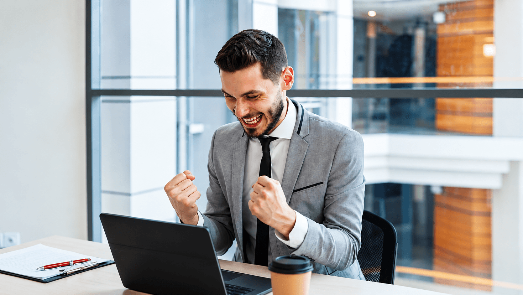 A professional celebrating a success at his laptop